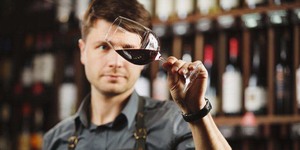 A man at a Red Wine Tasting holding up a glass of red wine