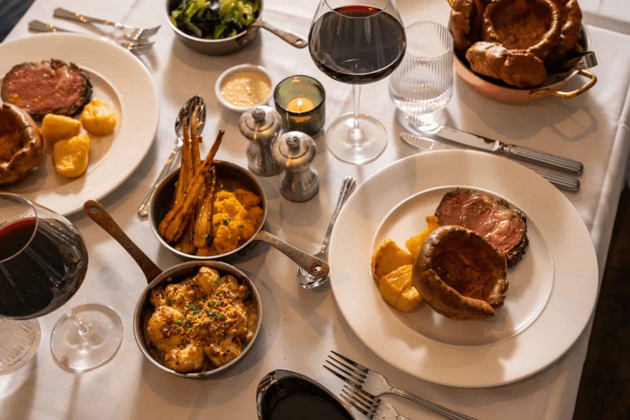 A Sunday roast laid out on a table with glasses of red wine at the Punch Bowl Pub