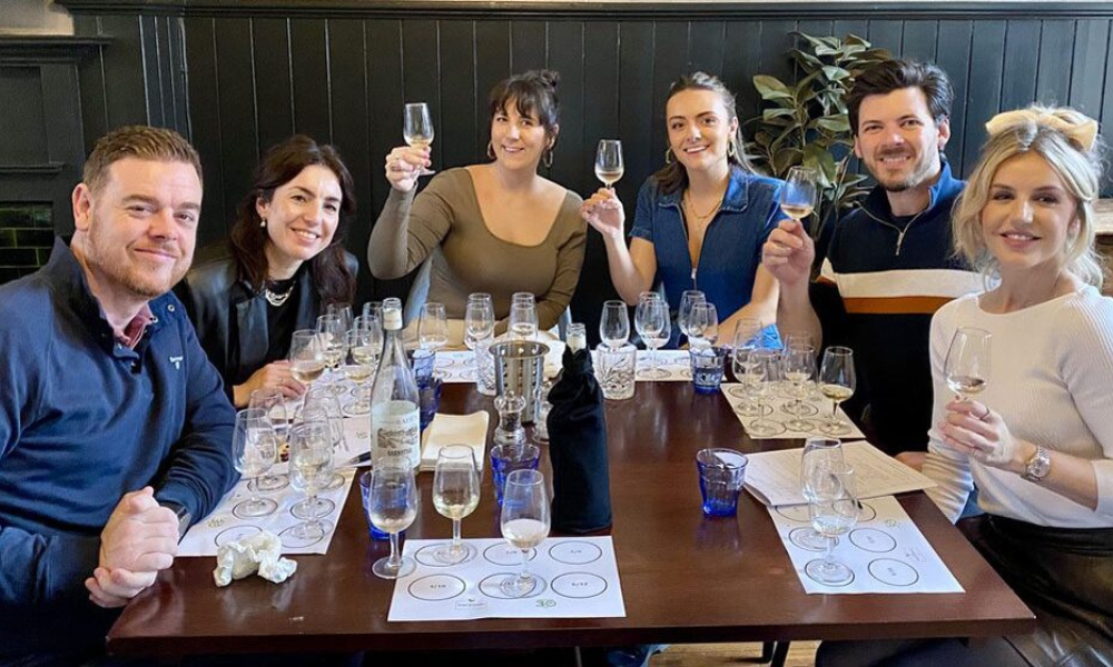three couples sitting at a table doing a wine tasting with tasting mats on the table in front of each person