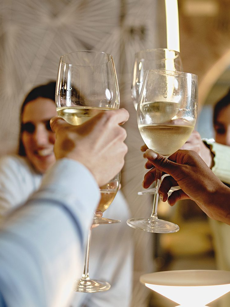 A group of four people toasting each other with glasses of white wine at a one day wine course in london
