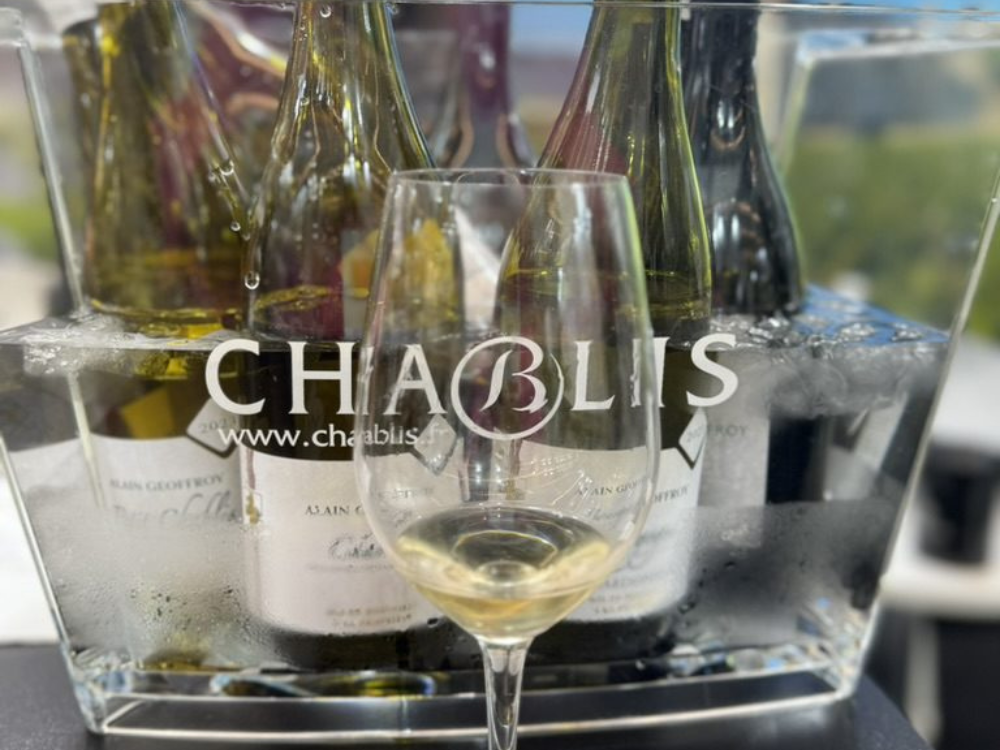 A glass of white wine infront of an ice bucket labelled "Chablis" at a one day wine tasting london