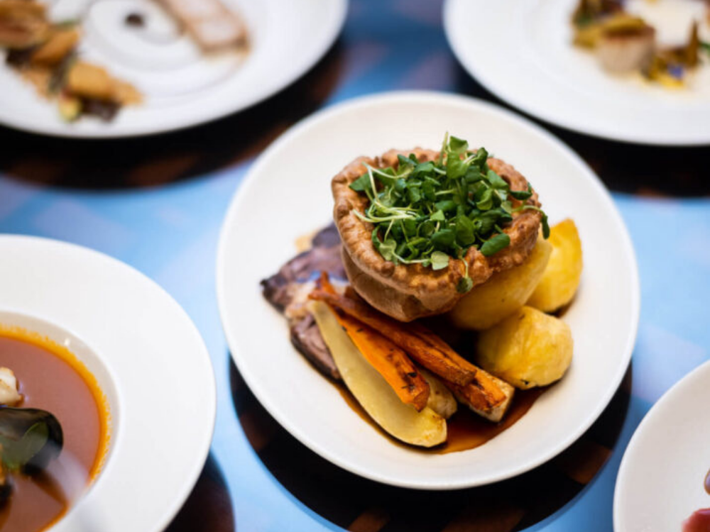 A yorkshire pudding plated atop vegetables