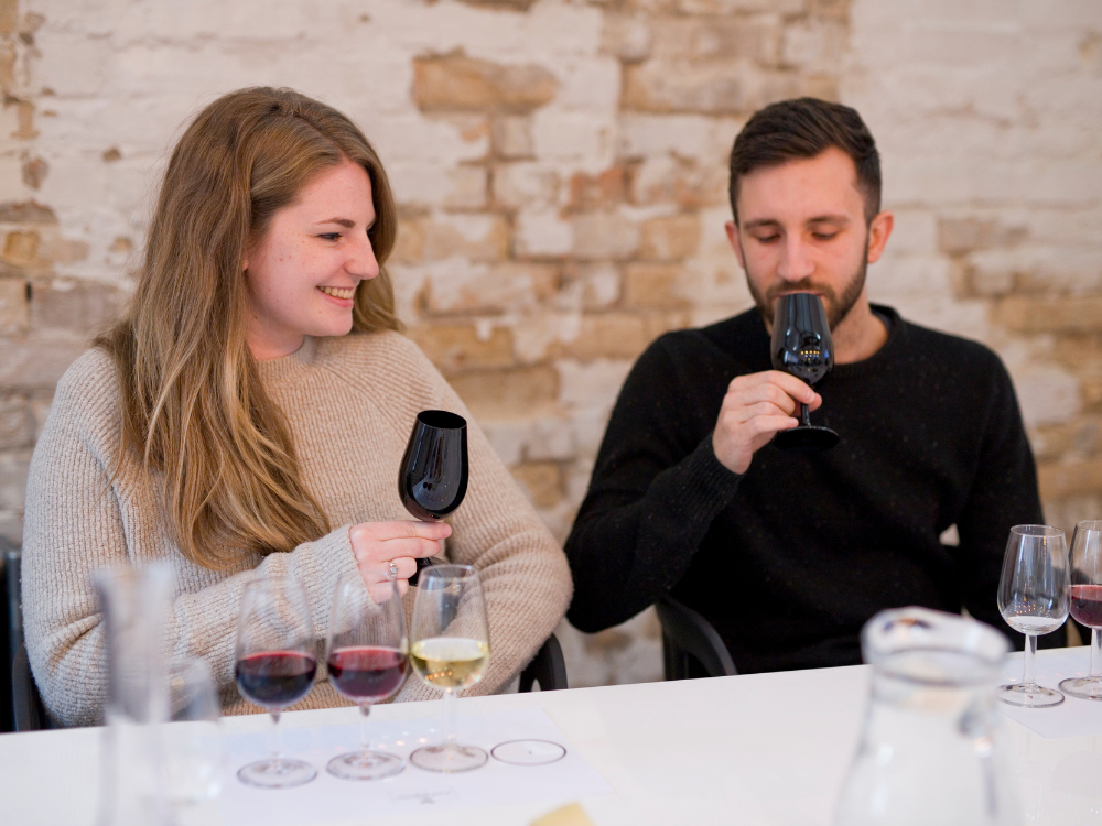A couple tasting wine from black wine glasses